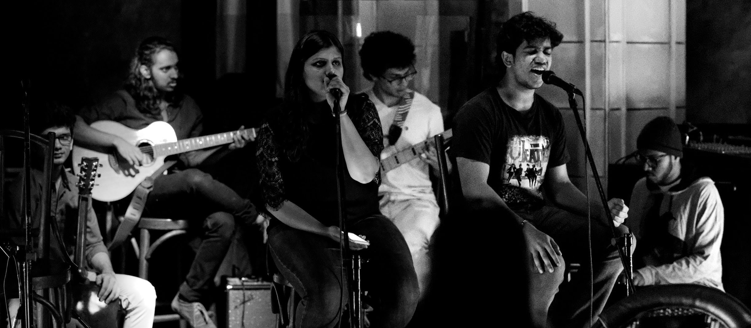 This is a black and white image of the band Blue Moss. From left to right, there is Ayush on Drums, Nirbhay on the Guitar, Shreya on vocals, Imaad on the bass, Vineet on vocals, and Rishi (me) on the synthesizer.